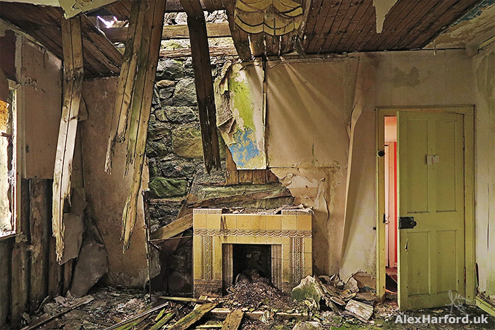 Collapsed roof fallen around small and old yellow fireplace
