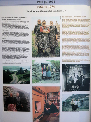 Photo of an info board. The text isn't legible but photos of inhabitants cam be seen including three eldery ladies wearing black and white dresses.