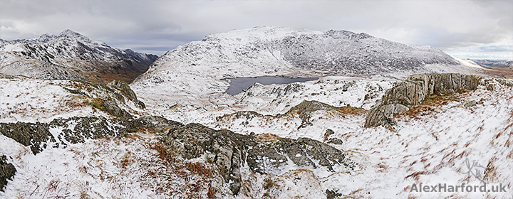Snow-covered Snowdon and Glyder Fach mountains from snowy Moel Berfedd summit