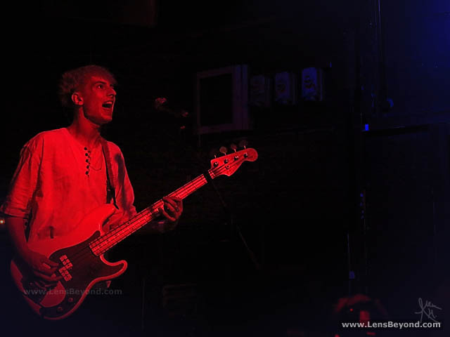 Theo Ellis, Wolf Alice bassist, lit by red stagelights